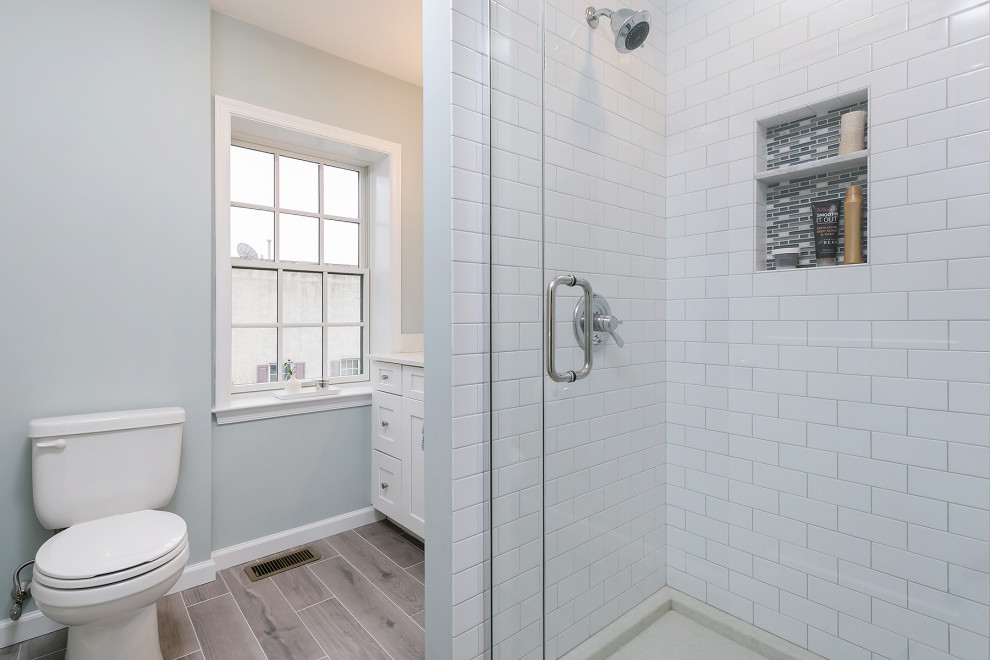 Idéer för ett litet modernt vit en-suite badrum, med släta luckor, vita skåp, en hörndusch, en toalettstol med hel cisternkåpa, grå väggar, ett nedsänkt handfat, bänkskiva i akrylsten, brunt golv och dusch med gångjärnsdörr