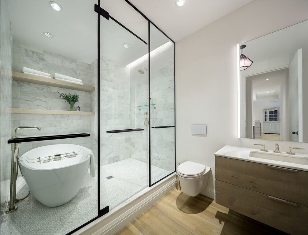 Идея дизайна: главная ванная комната в современном стиле с плоскими фасадами, светлыми деревянными фасадами, отдельно стоящей ванной, инсталляцией, белой плиткой, мраморной плиткой, белыми стенами, светлым паркетным полом, врезной раковиной, бежевым полом и открытым душем