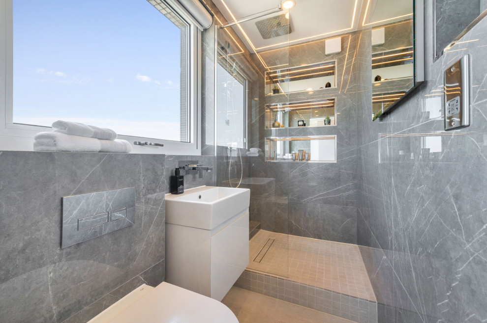 Photo of a contemporary bathroom in London with flat-panel cabinets, white cabinets, an alcove shower, a wall mounted toilet, grey tiles, a console sink, grey floors, an open shower, a single sink and a floating vanity unit.