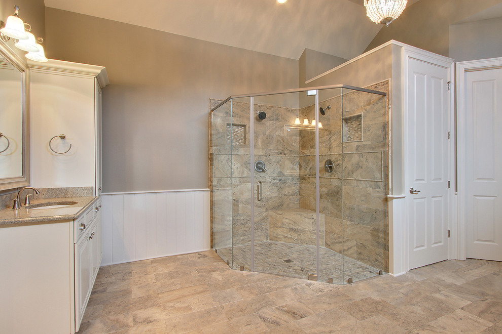 Exemple d'une douche en alcôve principale chic avec un lavabo encastré, un placard avec porte à panneau surélevé, des portes de placard blanches, un plan de toilette en granite, une baignoire posée, un carrelage beige, des carreaux de céramique, un mur gris et un sol en carrelage de céramique.