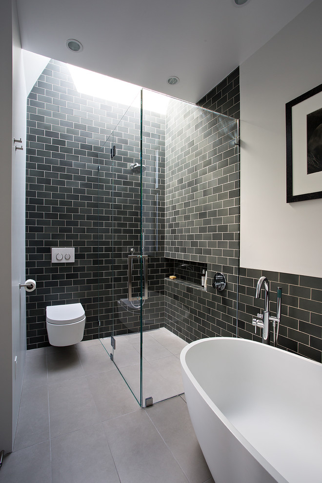 Idéer för ett mellanstort modernt en-suite badrum, med en vägghängd toalettstol, vita väggar, cementgolv, grått golv, ett fristående badkar, en kantlös dusch, tunnelbanekakel och dusch med gångjärnsdörr