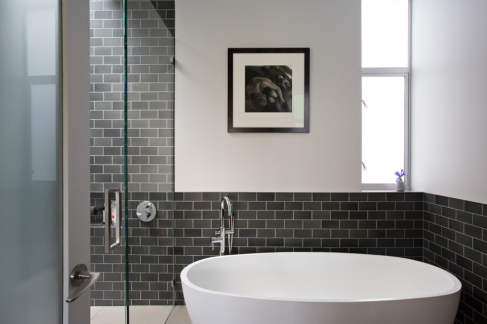 Inredning av ett modernt mellanstort en-suite badrum, med ett fristående badkar, en kantlös dusch, en vägghängd toalettstol, tunnelbanekakel, vita väggar, cementgolv, grått golv och dusch med gångjärnsdörr