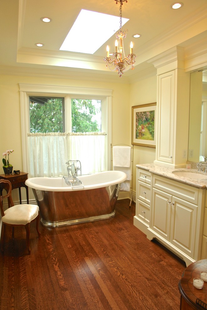Idéer för att renovera ett mellanstort vintage en-suite badrum, med möbel-liknande, vita skåp, marmorbänkskiva, ett fristående badkar, beige kakel, stenhäll, vita väggar och mellanmörkt trägolv