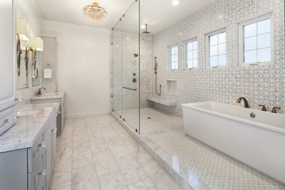 Réalisation d'une très grande salle de bain principale design avec un placard avec porte à panneau surélevé, des portes de placard grises, une baignoire indépendante, une douche d'angle, un carrelage gris, un mur blanc, un lavabo encastré, un sol gris et un plan de toilette gris.
