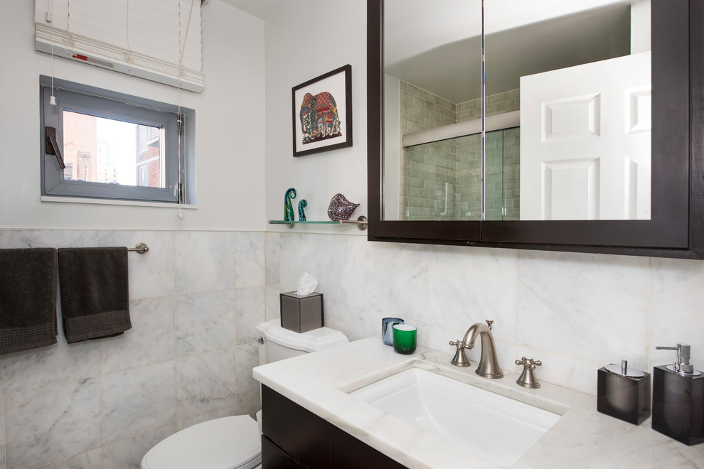 Inspiration for a small timeless 3/4 stone tile marble floor doorless shower remodel in New York with flat-panel cabinets, dark wood cabinets, a one-piece toilet, white walls, an undermount sink and marble countertops