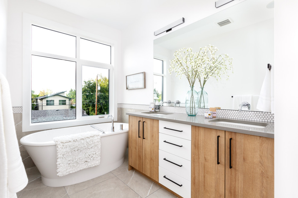 Idée de décoration pour une salle de bain design en bois brun avec un placard à porte plane, une baignoire indépendante, un carrelage blanc, mosaïque, un mur blanc, un lavabo encastré, un sol gris et un plan de toilette gris.