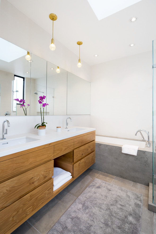Foto på ett mellanstort funkis en-suite badrum, med släta luckor, skåp i ljust trä, ett badkar i en alkov, grå kakel, vita väggar, ett undermonterad handfat, travertin golv och beiget golv