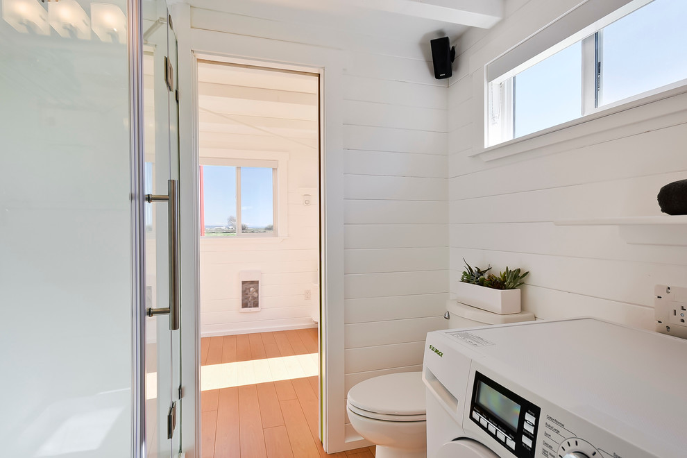 Aménagement d'une petite salle de bain principale contemporaine avec un placard à porte plane, des portes de placard blanches, une douche d'angle, WC à poser, un mur blanc et parquet clair.