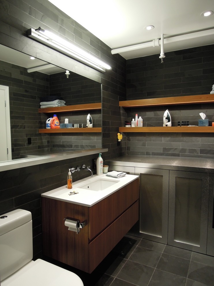 Imagen de cuarto de baño contemporáneo con lavabo bajoencimera, armarios con paneles lisos, puertas de armario de madera en tonos medios y baldosas y/o azulejos grises