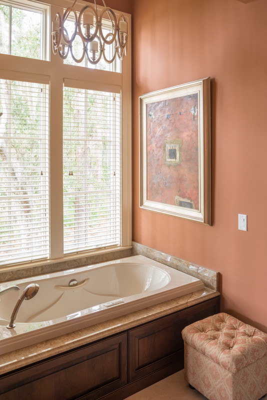 Esempio di una grande stanza da bagno padronale tradizionale con ante con bugna sagomata, ante in legno scuro, vasca freestanding, piastrelle beige, lastra di vetro, pareti arancioni, pavimento in travertino, lavabo sottopiano e top in granito