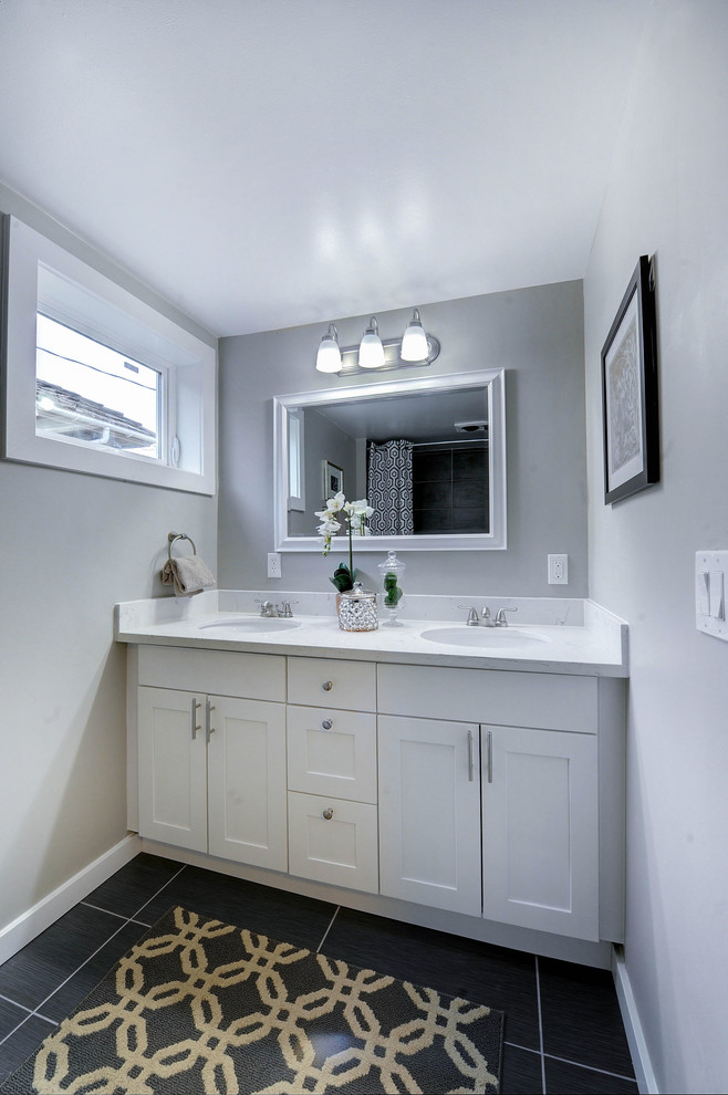 Cette image montre une salle de bain traditionnelle avec un lavabo encastré, un placard à porte shaker, des portes de placard blanches, un plan de toilette en quartz modifié, un carrelage gris, des carreaux de céramique, un mur gris et un sol en carrelage de céramique.