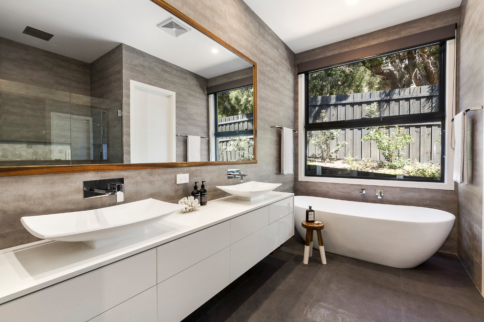 Contemporary ensuite bathroom in Melbourne with flat-panel cabinets, white cabinets, a freestanding bath, grey walls, a vessel sink and grey floors.