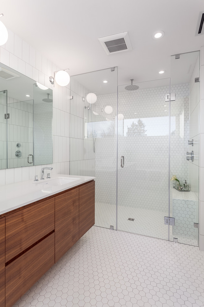 Foto på ett funkis badrum, med släta luckor, skåp i mörkt trä, en kantlös dusch, vit kakel, mosaik, vita väggar, mosaikgolv, ett undermonterad handfat och dusch med gångjärnsdörr