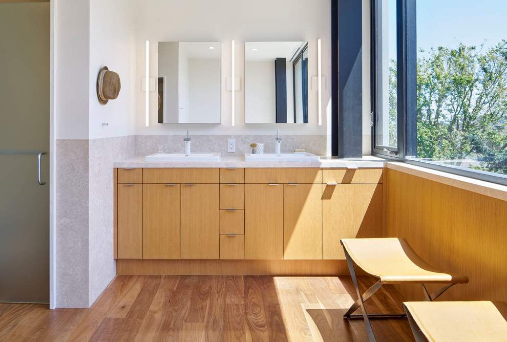 Пример оригинального дизайна: огромная главная ванная комната в стиле модернизм с плоскими фасадами, фасадами цвета дерева среднего тона, унитазом-моноблоком, белыми стенами, темным паркетным полом и мраморной столешницей