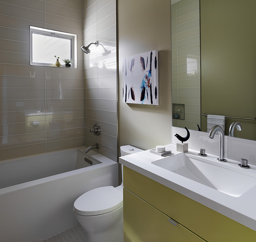 Idee per una stanza da bagno minimal con lavabo sottopiano, ante lisce, ante gialle, vasca sottopiano, vasca/doccia, WC a due pezzi e piastrelle grigie