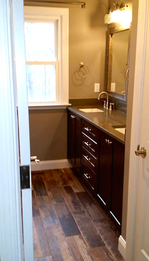 Inspiration pour une salle de bain principale craftsman en bois foncé de taille moyenne avec un placard avec porte à panneau encastré, un mur gris, un sol en bois brun, un lavabo encastré, un plan de toilette en stratifié et un sol marron.