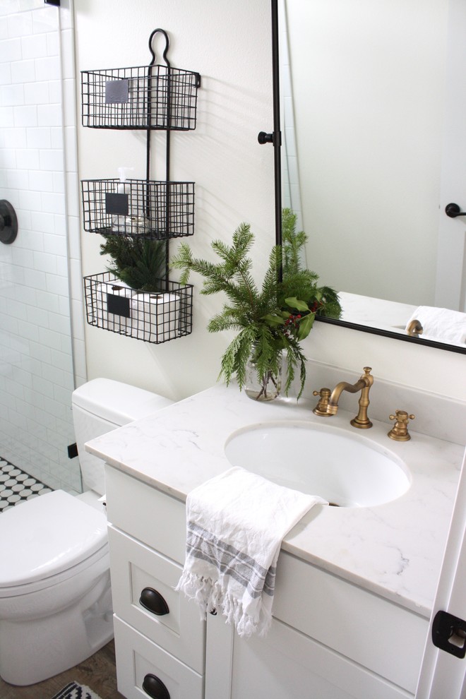 Aménagement d'une petite salle de bain campagne avec un placard à porte shaker, des portes de placard blanches, WC à poser, un carrelage gris, un carrelage métro, un mur blanc, un sol en vinyl, un lavabo encastré et un plan de toilette en quartz modifié.