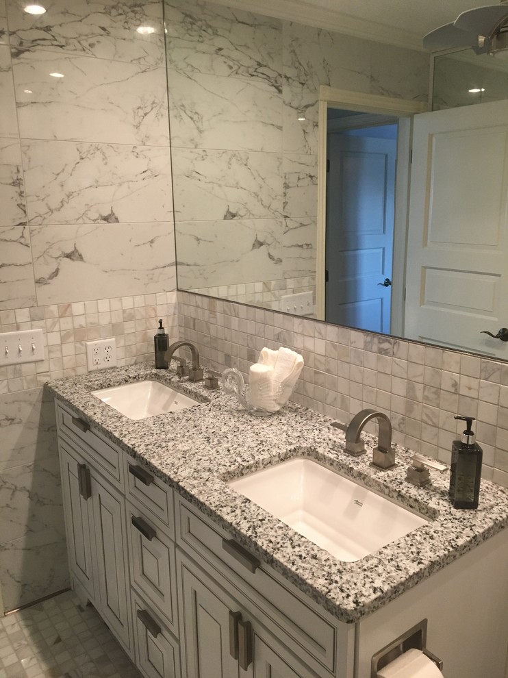 Photo of a medium sized traditional ensuite bathroom in Other with raised-panel cabinets, white cabinets, a freestanding bath, grey tiles, white tiles, marble tiles, grey walls, marble flooring, a submerged sink, granite worktops, grey floors and grey worktops.