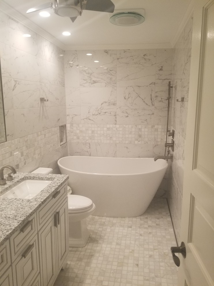 Inspiration för mellanstora klassiska grått en-suite badrum, med luckor med upphöjd panel, vita skåp, ett fristående badkar, grå kakel, vit kakel, marmorkakel, grå väggar, marmorgolv, ett undermonterad handfat, granitbänkskiva och grått golv