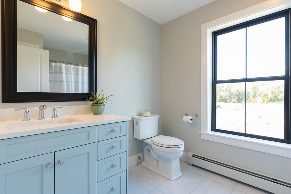 Kleines Landhaus Badezimmer mit Schrankfronten im Shaker-Stil, blauen Schränken, Wandtoilette mit Spülkasten, beiger Wandfarbe, Keramikboden, Unterbauwaschbecken, grauem Boden und weißer Waschtischplatte in Portland Maine