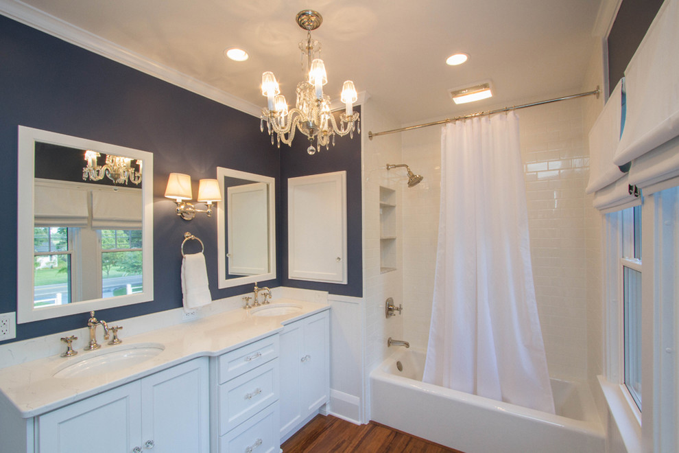 This is an example of a large traditional family bathroom in Other with raised-panel cabinets, white cabinets, an alcove bath, a shower/bath combination, a two-piece toilet, white tiles, ceramic tiles, blue walls, bamboo flooring, a submerged sink, granite worktops, brown floors and a shower curtain.
