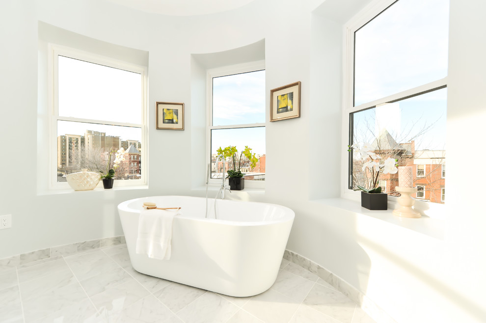 На фото: ванная комната в современном стиле с отдельно стоящей ванной, белыми стенами и мраморным полом с