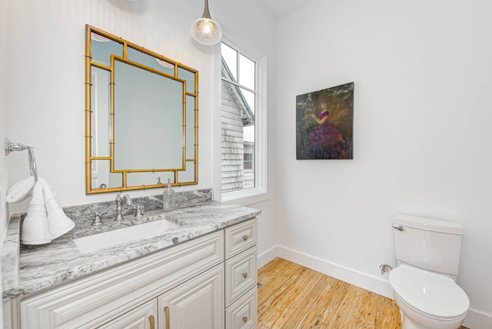 Foto på ett mellanstort vintage grå badrum, med släta luckor, skåp i ljust trä, en toalettstol med hel cisternkåpa, vita väggar, ljust trägolv, ett nedsänkt handfat, marmorbänkskiva och brunt golv