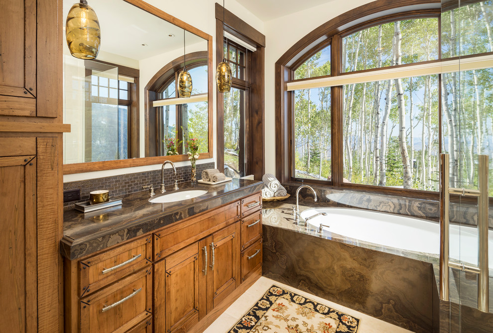 Inspiration for a medium sized rustic ensuite bathroom in Salt Lake City with medium wood cabinets, a submerged bath, beige walls, a submerged sink, beige floors, brown worktops, recessed-panel cabinets and granite worktops.