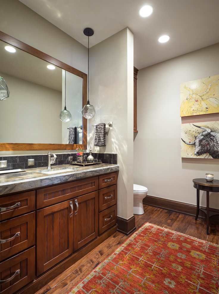 Idée de décoration pour une très grande salle de bain chalet en bois brun avec un placard à porte plane et un plan de toilette en marbre.