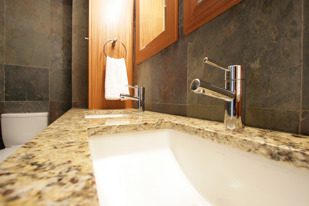 Klassisk inredning av ett badrum, med ett undermonterad handfat, granitbänkskiva, flerfärgad kakel, stenkakel och skiffergolv