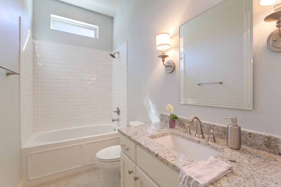 Mid-sized trendy subway tile ceramic tile bathroom photo in New Orleans with recessed-panel cabinets, white cabinets, a two-piece toilet, gray walls, an undermount sink and granite countertops