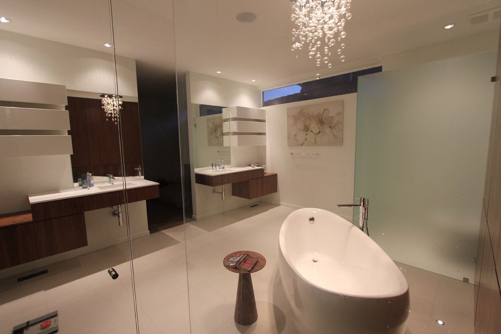 This is an example of a large modern ensuite bathroom in Vancouver with a submerged sink, flat-panel cabinets, medium wood cabinets, granite worktops, a freestanding bath, a corner shower, a one-piece toilet, beige tiles, porcelain tiles, white walls and porcelain flooring.