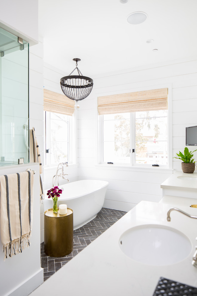 На фото: ванная комната в морском стиле с белыми фасадами, отдельно стоящей ванной, белыми стенами, врезной раковиной, серым полом и бежевой столешницей
