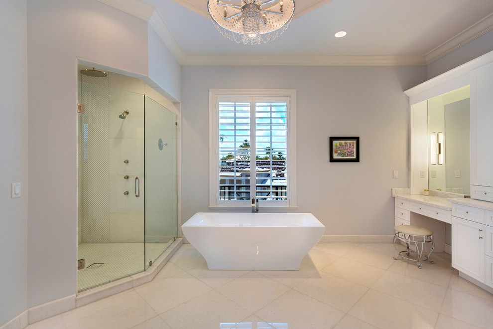 Свежая идея для дизайна: огромная главная ванная комната в морском стиле с фасадами с утопленной филенкой, белыми фасадами, душем в нише, унитазом-моноблоком, серой плиткой, мраморной плиткой, белыми стенами, врезной раковиной, мраморной столешницей, душем с распашными дверями, серой столешницей, отдельно стоящей ванной, полом из керамогранита и бежевым полом - отличное фото интерьера