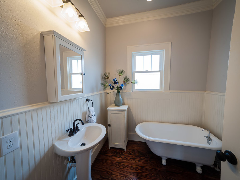 Esempio di una stanza da bagno stile americano di medie dimensioni con lavabo a colonna, vasca con piedi a zampa di leone, pareti bianche e pavimento in legno massello medio