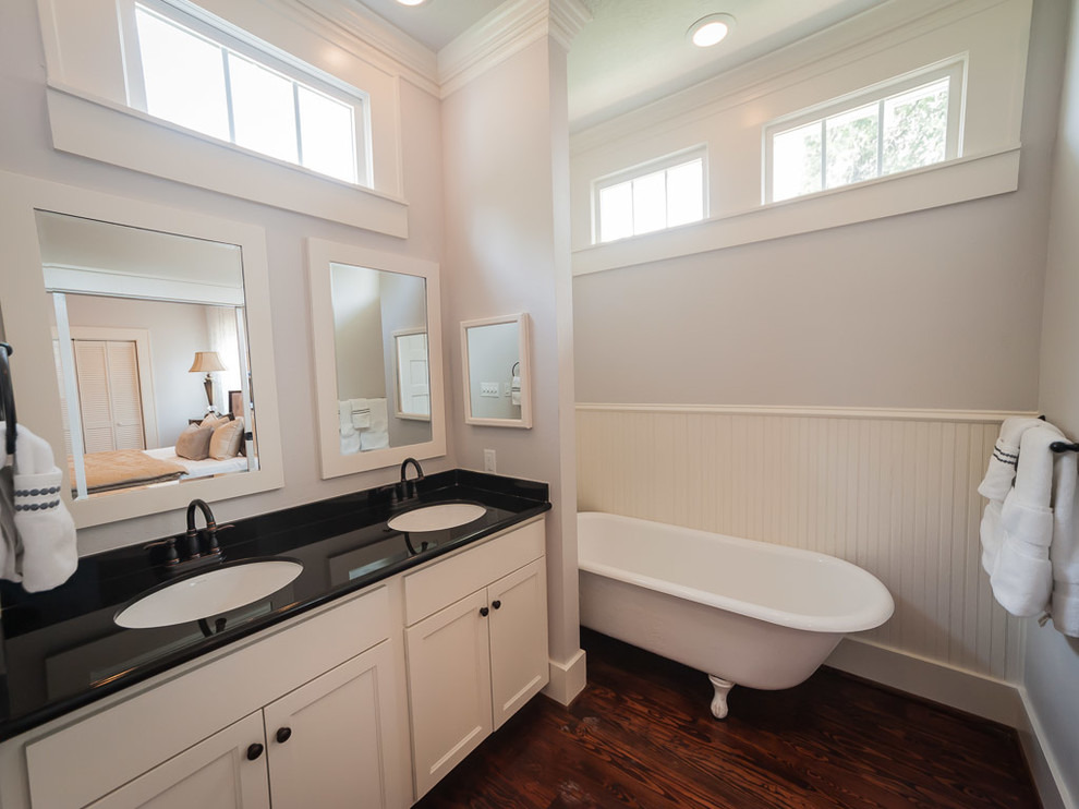 Foto på ett mellanstort amerikanskt en-suite badrum, med ett undermonterad handfat, skåp i shakerstil, vita skåp, granitbänkskiva, ett badkar med tassar, vita väggar och mellanmörkt trägolv