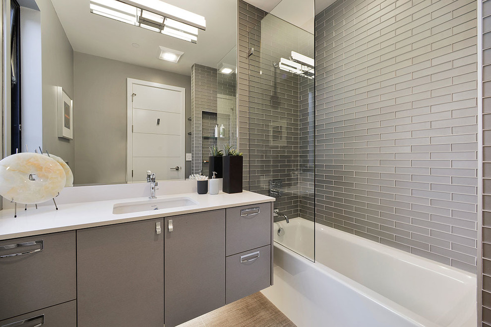 Modern inredning av ett en-suite badrum, med släta luckor, grå skåp, ett badkar i en alkov, en dusch/badkar-kombination, grå kakel, grå väggar, ett undermonterad handfat och med dusch som är öppen