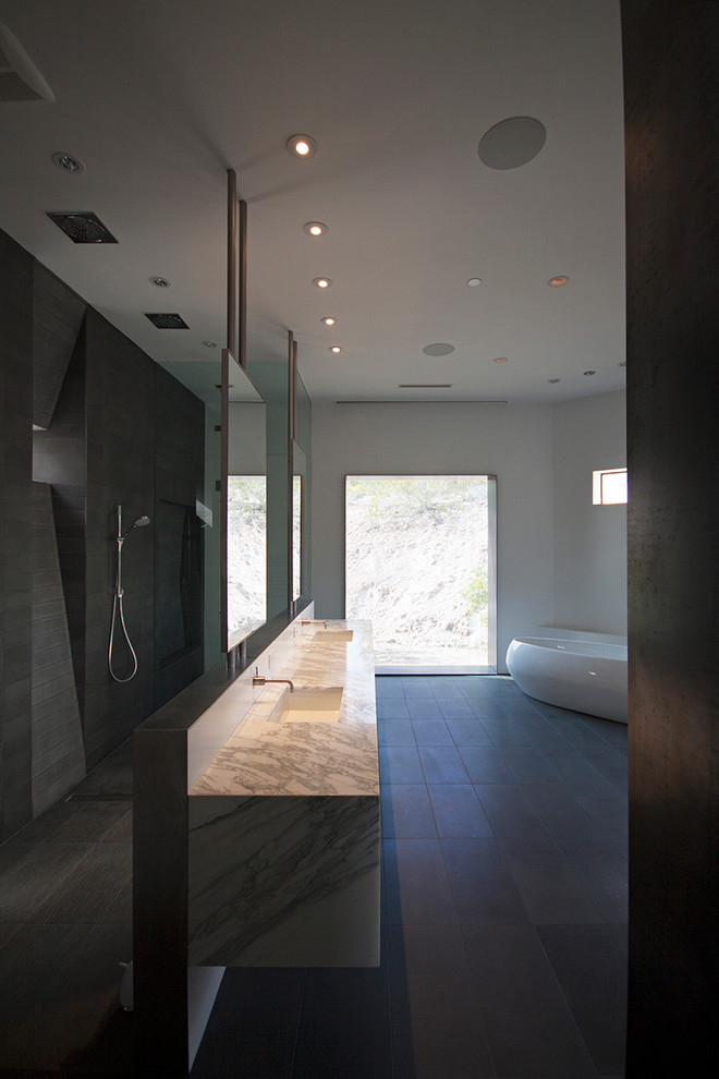 Example of a minimalist master gray tile and stone tile bathroom design in Phoenix with flat-panel cabinets, medium tone wood cabinets, a one-piece toilet, white walls, an undermount sink and marble countertops