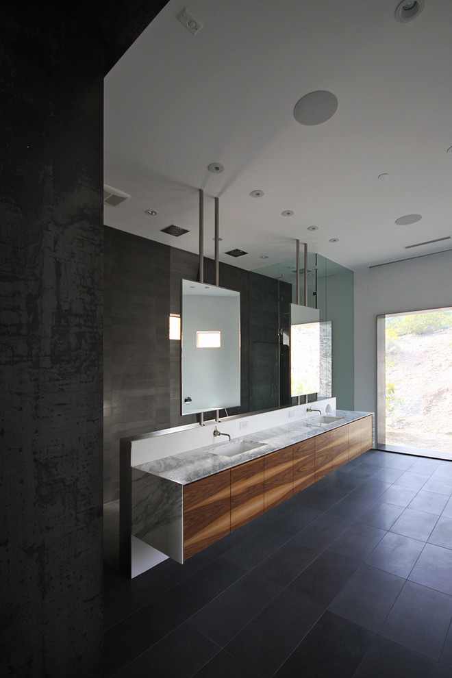 Idées déco pour une salle de bain principale moderne en bois brun avec un placard à porte plane, une baignoire indépendante, une douche ouverte, WC à poser, un carrelage gris, un carrelage de pierre, un mur blanc, un lavabo encastré et un plan de toilette en marbre.