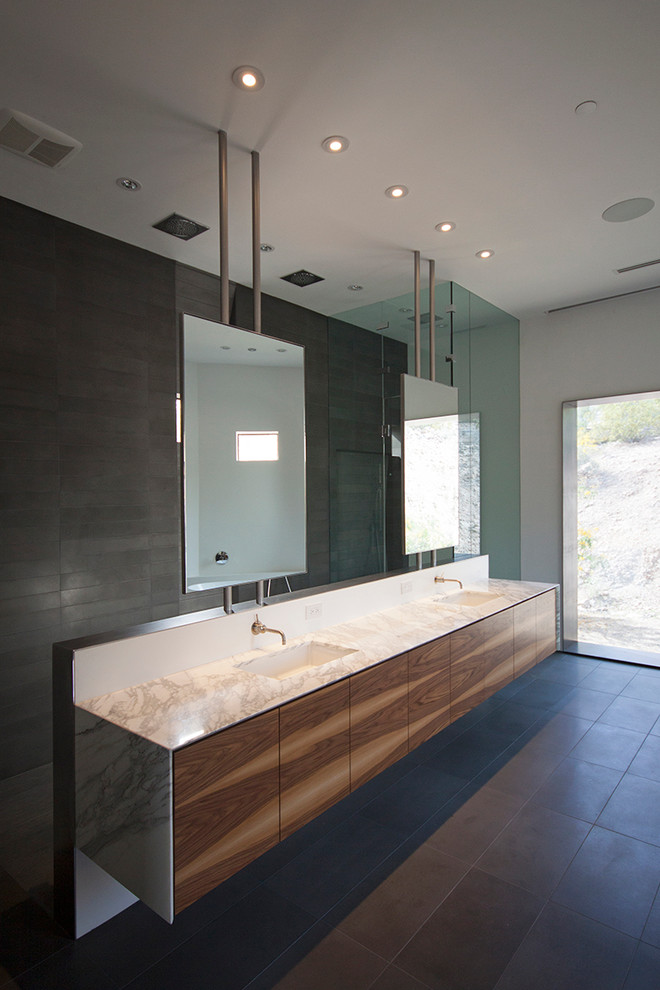 Example of a large minimalist master gray tile and stone tile bathroom design in Phoenix with flat-panel cabinets, medium tone wood cabinets, a one-piece toilet, white walls, an undermount sink and marble countertops