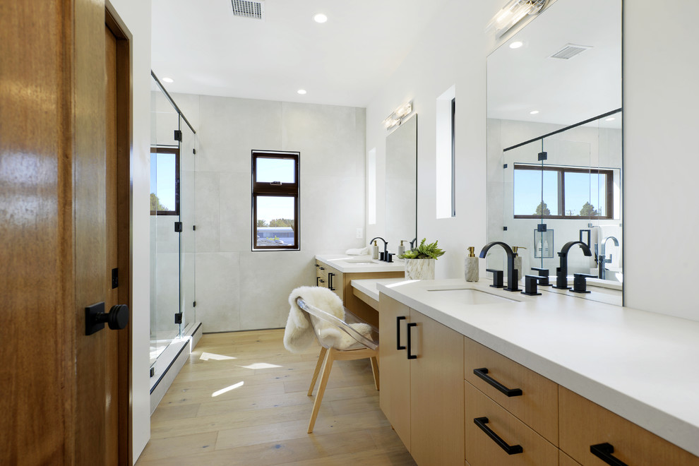 На фото: главная ванная комната в современном стиле с плоскими фасадами, светлыми деревянными фасадами, белой плиткой, белыми стенами, светлым паркетным полом, врезной раковиной, бежевым полом и белой столешницей с