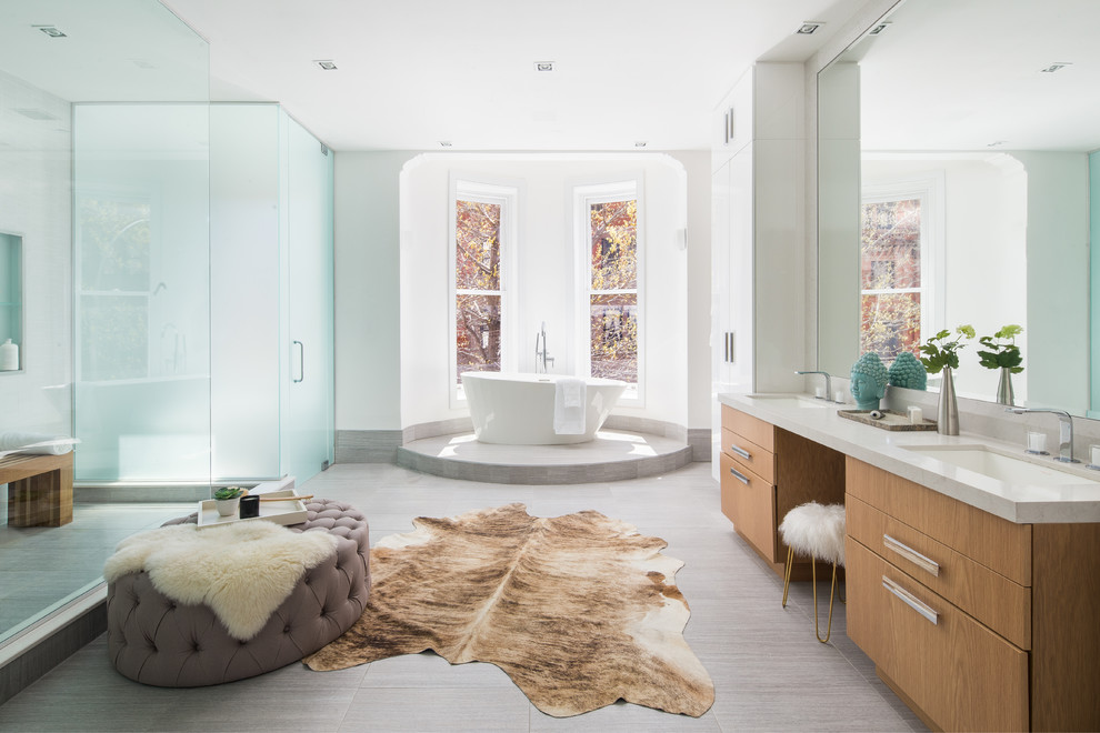 Modelo de cuarto de baño contemporáneo con armarios con paneles lisos, puertas de armario de madera oscura, bañera exenta, ducha abierta, paredes blancas, lavabo bajoencimera y suelo gris