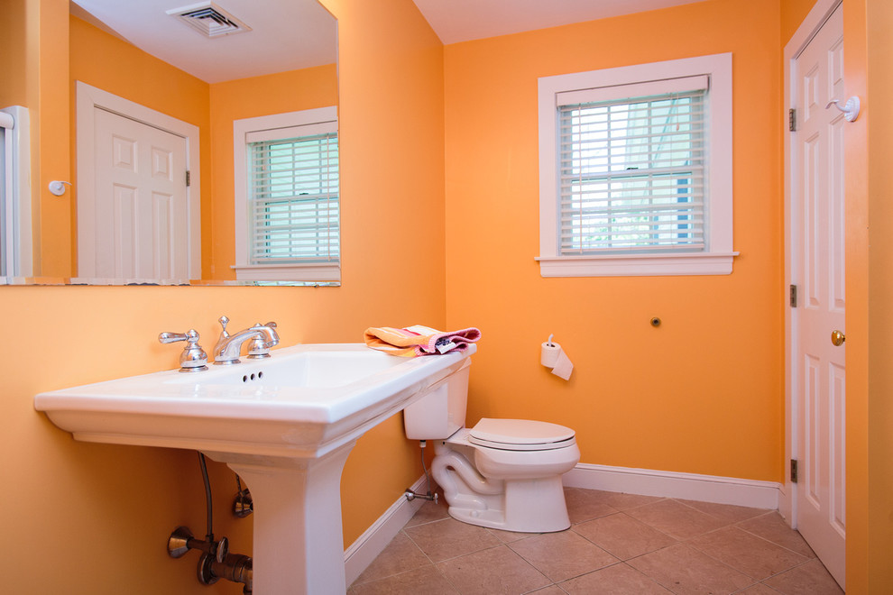 На фото: ванная комната в классическом стиле с фасадами цвета дерева среднего тона, угловой ванной, угловым душем, оранжевыми стенами, душевой кабиной и раковиной с пьедесталом