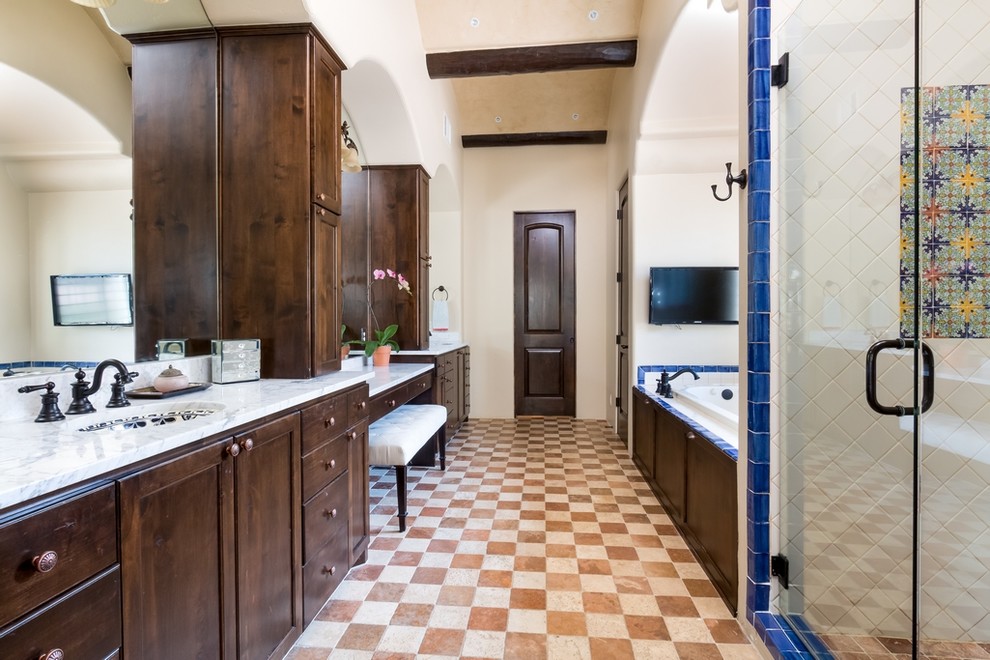 Свежая идея для дизайна: главная ванная комната в средиземноморском стиле с темными деревянными фасадами, накладной ванной, душем в нише, синей плиткой, разноцветной плиткой, белой плиткой, бежевыми стенами, врезной раковиной, разноцветным полом, душем с распашными дверями и фасадами с утопленной филенкой - отличное фото интерьера