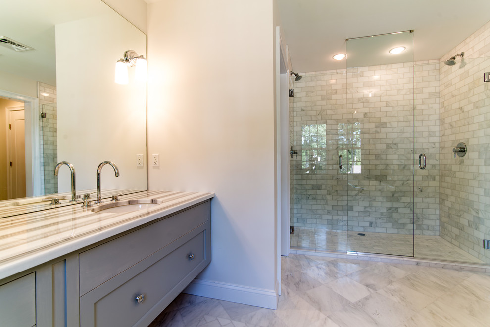 Example of a mid-sized classic master white tile and stone tile porcelain tile and white floor wet room design in New York with white walls, beaded inset cabinets, gray cabinets, an undermount sink, quartz countertops and a hinged shower door