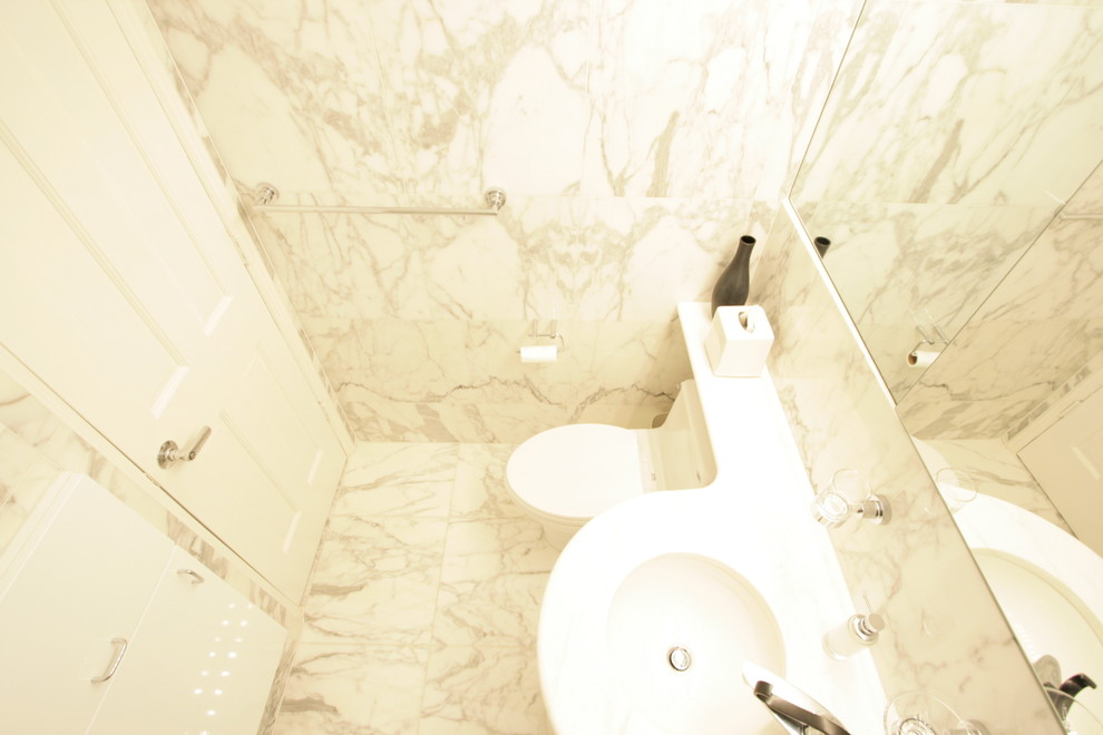 Réalisation d'une petite salle de bain design avec un placard à porte plane, des portes de placard blanches, un carrelage de pierre, un sol en marbre et un plan de toilette en marbre.