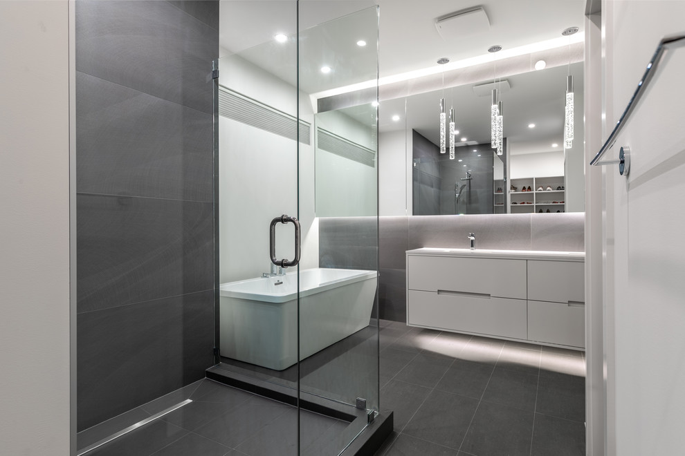 Medium sized modern ensuite bathroom with raised-panel cabinets, white cabinets, a freestanding bath, a corner shower, a one-piece toilet, white walls, a submerged sink, engineered stone worktops and a hinged door.