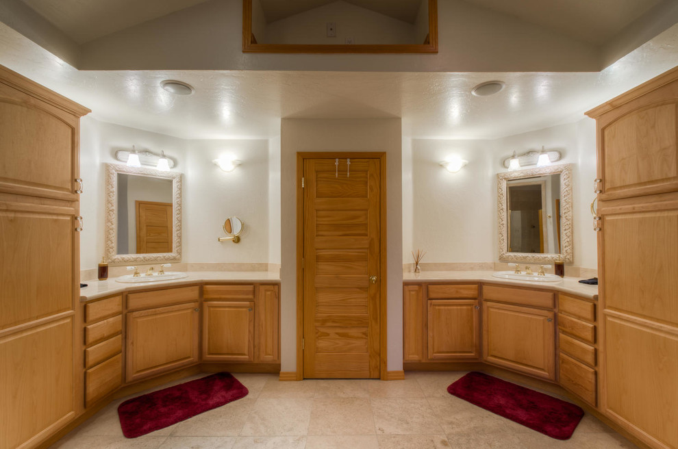Exemple d'une grande salle de bain principale chic en bois clair avec un lavabo posé, un placard avec porte à panneau surélevé, un plan de toilette en stratifié, une baignoire en alcôve, une douche d'angle, WC à poser, un carrelage beige, un carrelage de pierre, un mur beige et un sol en carrelage de céramique.