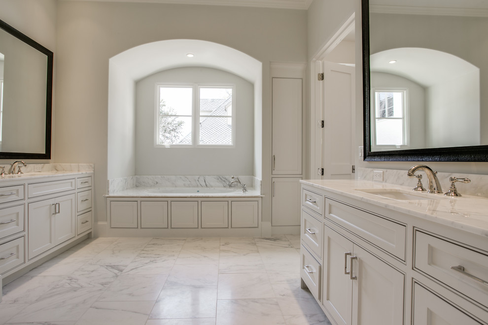 Foto de cuarto de baño principal tradicional grande con armarios con rebordes decorativos, puertas de armario blancas, encimera de mármol y jacuzzi