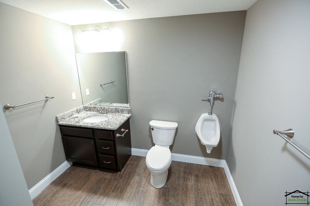 Foto de cuarto de baño principal grande con puertas de armario de madera en tonos medios, ducha abierta, urinario, paredes grises, suelo de baldosas de cerámica, lavabo bajoencimera y encimera de granito